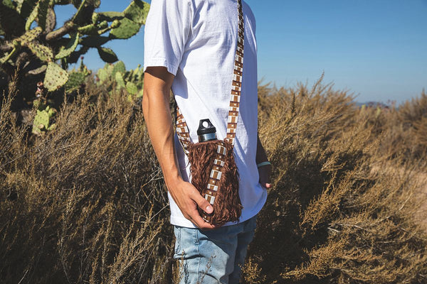 Person outdoors carrying furry crossbody bottle holder in desert with cactus background