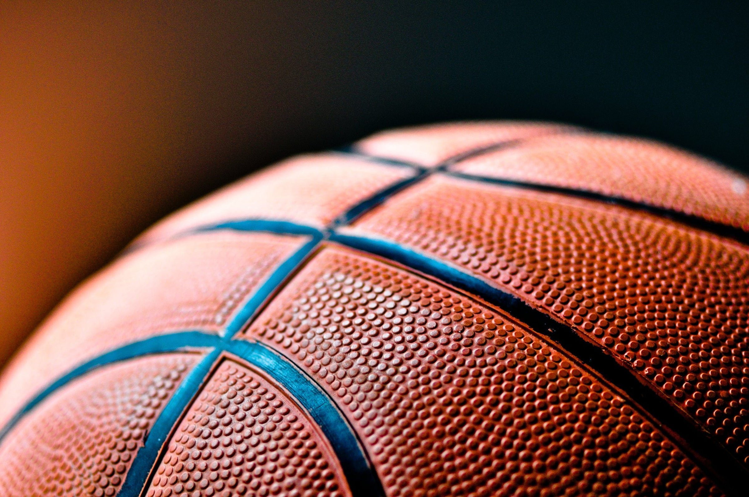 Close-up view of textured basketball surface with black seams and shallow focus.