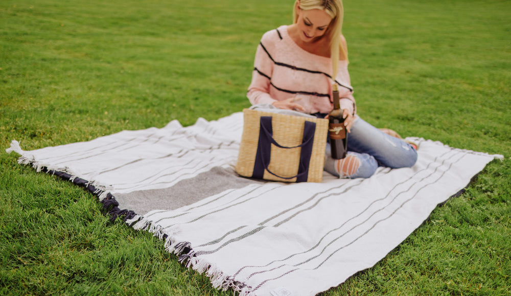 woman sitting on picnic blanket with picnic tote