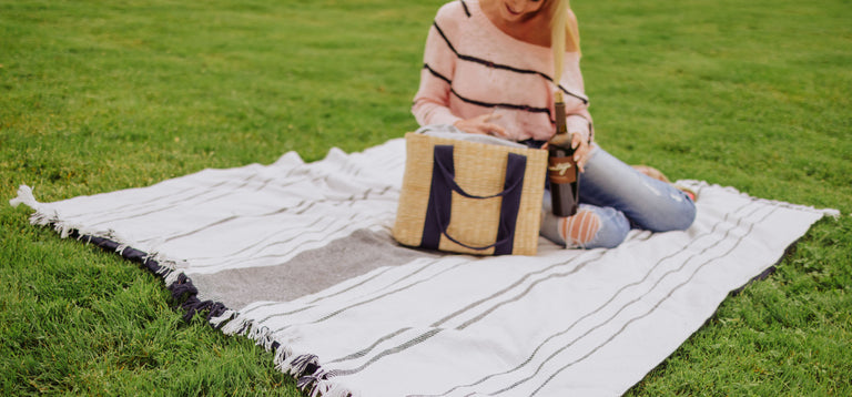 woman sitting on picnic blanket with picnic tote