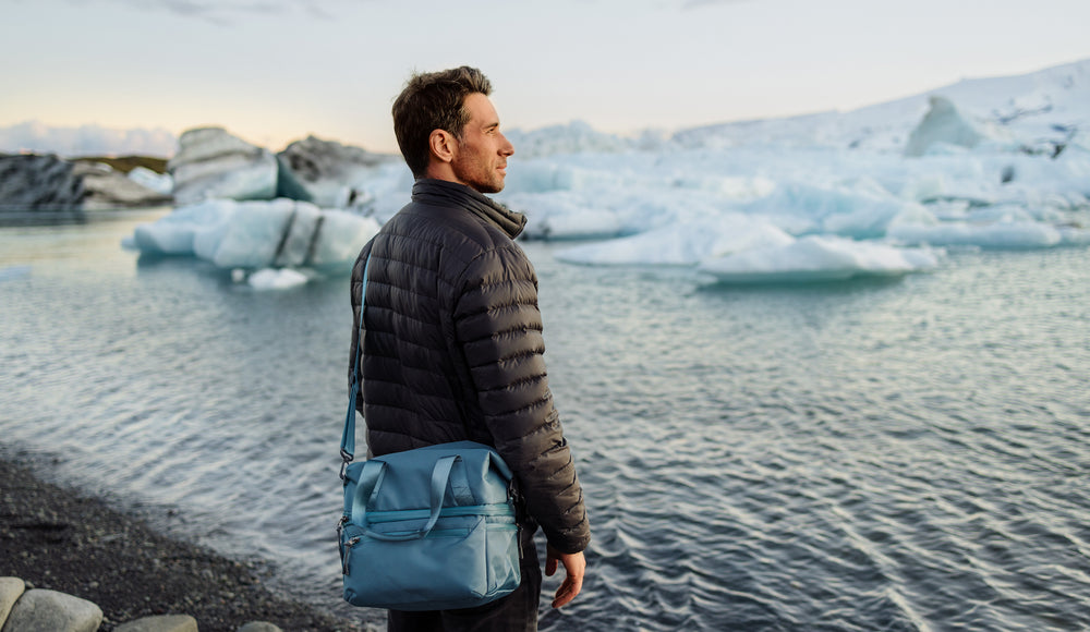 Person carrying a picnic tote next to an icy waterscape