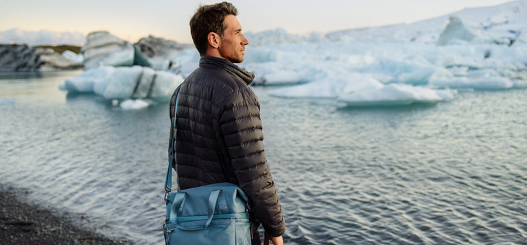Person carrying a picnic tote next to an icy waterscape