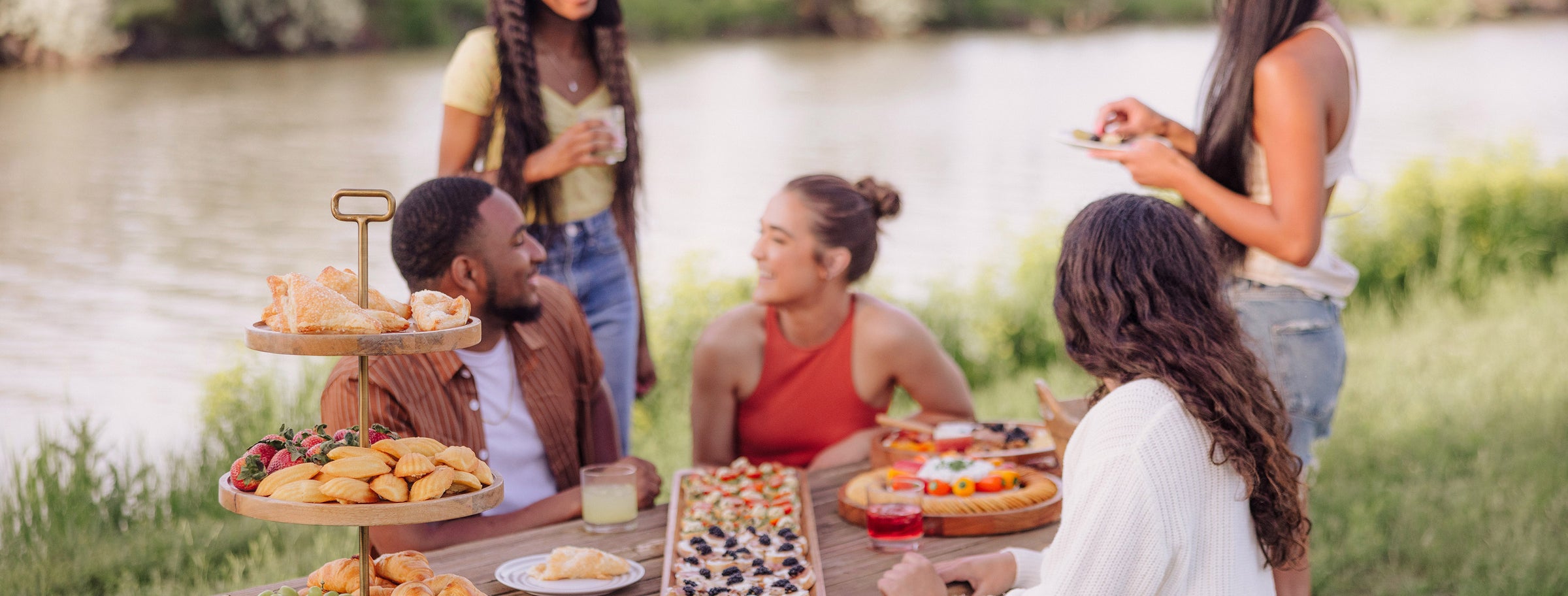 A group of people enjoying a meal together at a picnic table filled with various foods and drinks.